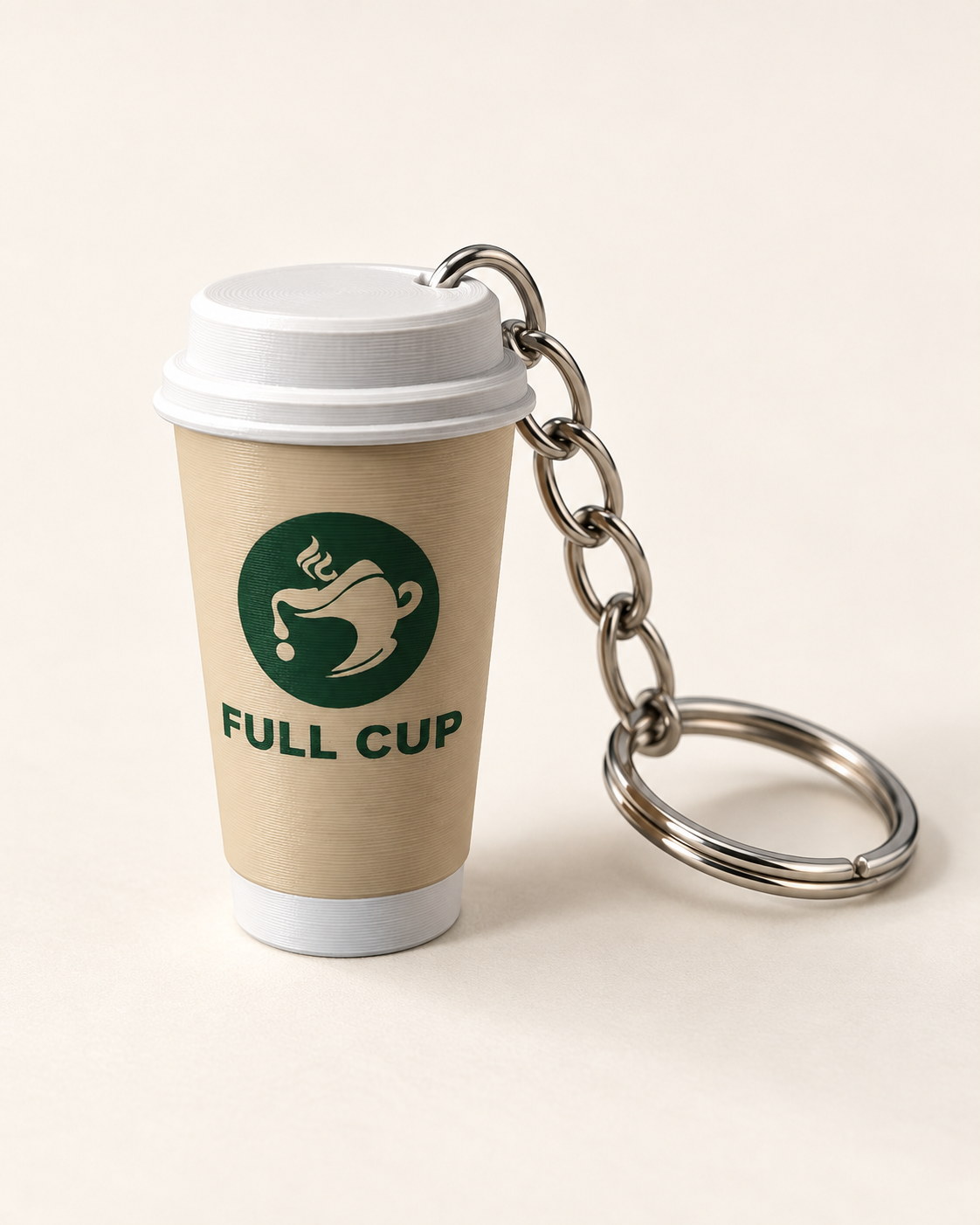 تصوّر واقعي مولّد لميدالية Full Cup: كوب كريمي وغطاء وقاعدة بيضاء وشعار أخضر، بسلسلة وحلقة مفاتيح فضية متصلة بالغطاء